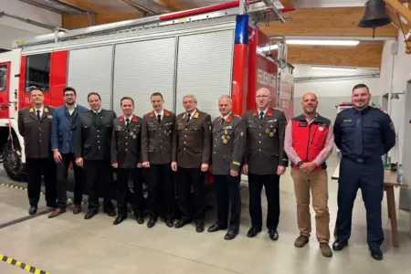 Eine Gruppe von Personen, teilweise in Uniform, vor einem Feuerwehrfahrzeug