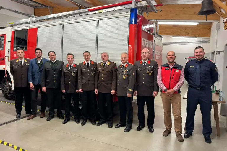 Eine Gruppe von Personen, teilweise in Uniform, vor einem Feuerwehrfahrzeug
