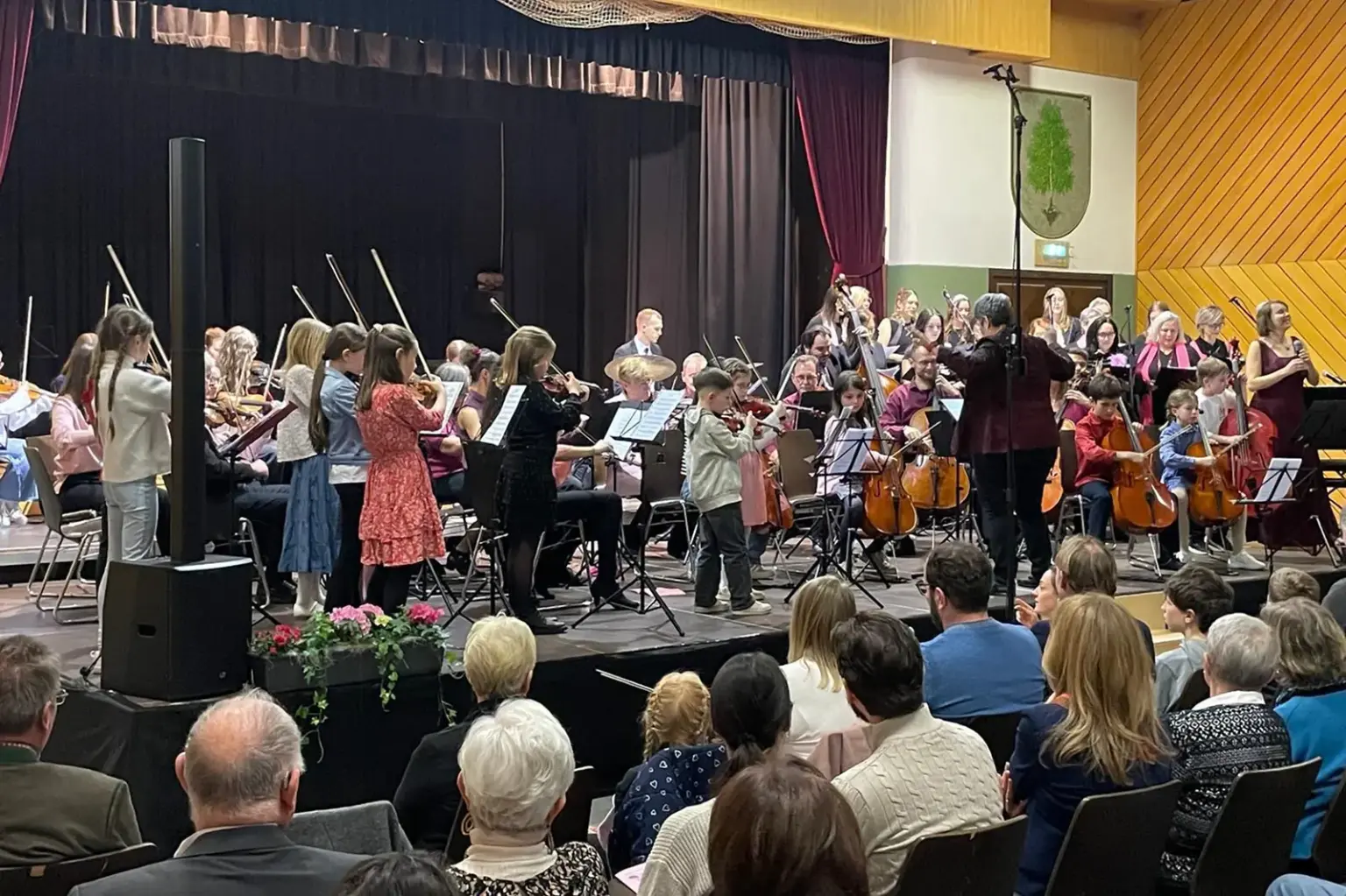 Ein Orchester mit vielen Kindern vor Publikum auf einer Bühne