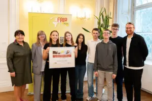 Eine Gruppe von Jugendlichen und Erwachsenen mit einer Urkunde