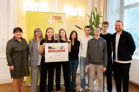 Eine Gruppe von Jugendlichen und Erwachsenen mit einer Urkunde