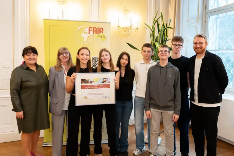 Eine Gruppe von Jugendlichen und Erwachsenen mit einer Urkunde