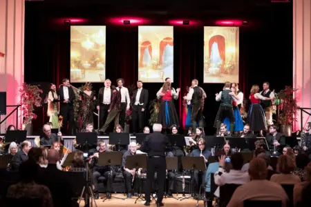 Es ist eine Bühne mit tanzenden Menschen zu sehen, davor sitzen Musiker.