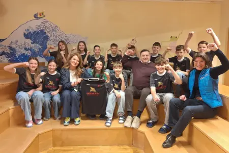 Eine Gruppe von Schülern mit drei Erwachsenen präsentieren T-Shirts