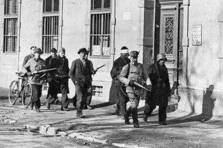 Eine alte Schwarzweiß-Aufnahme von bewaffenten Männern mit Gefangenen