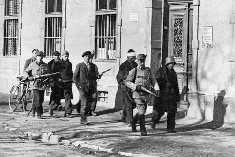 Eine alte Schwarzweiß-Aufnahme von bewaffenten Männern mit Gefangenen