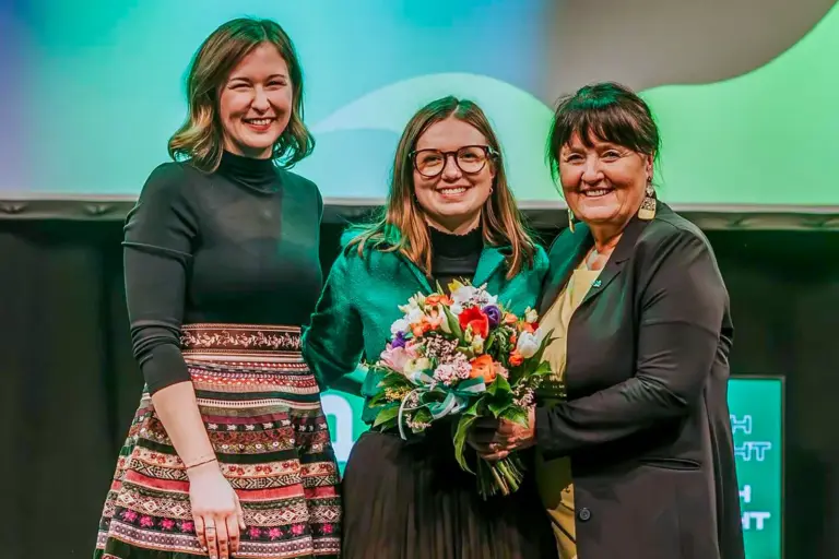 Drei lächelnde Frauen auf einer Bühne