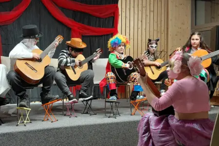 Eine Gruppe junger MusikerInnen in bunten Kostümen spielen Gitarre auf einer Bühne