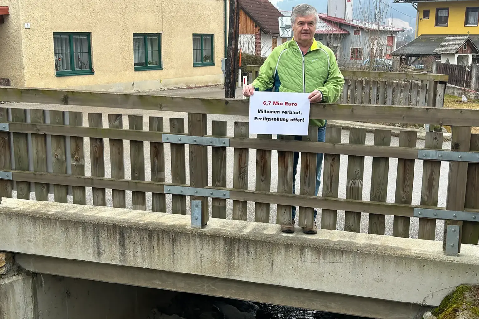Ein Mann mit einem Schild auf einer Brücke über einen Bach
