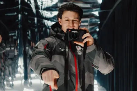 Ein Mann steht mit einer Kamera in der Hand vor einem Spiegel.