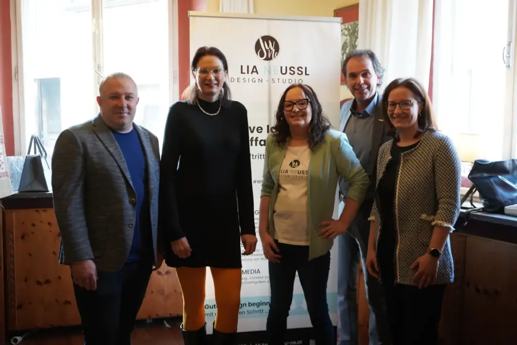 Fünf Personen, zwei Männer und drei Frauen stehen nebeneinander und lächeln in die Kamera.