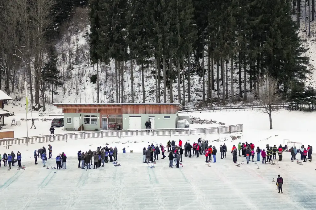Eine Eisbahn mit vielen Personen und einer Hütte im Hintergrund