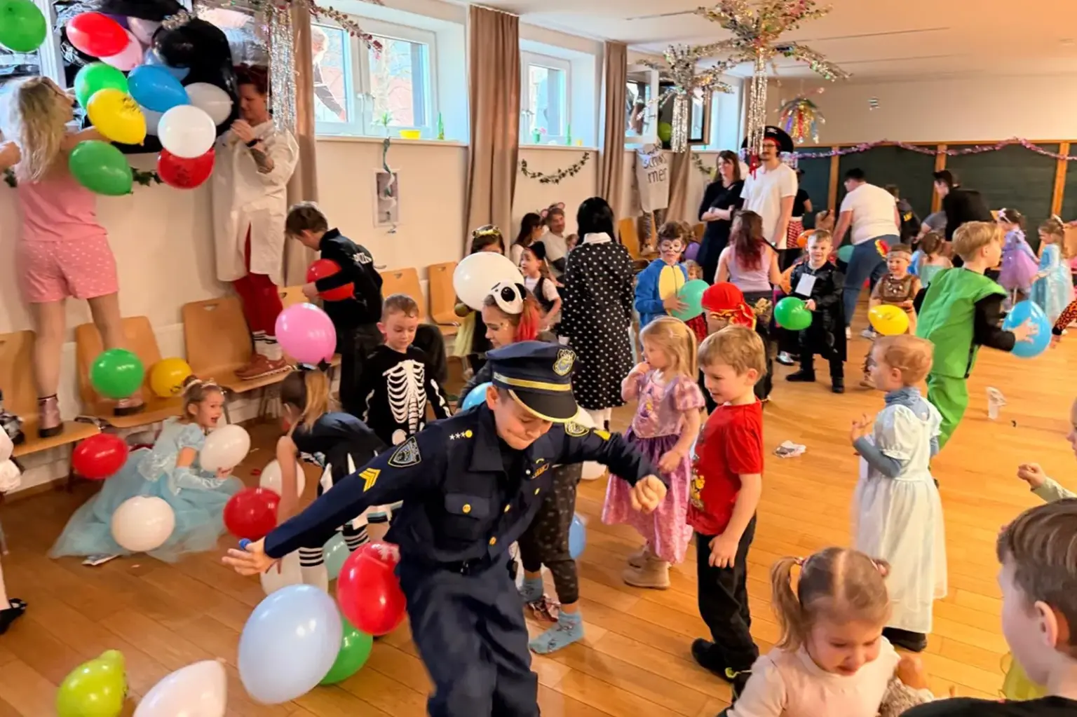 Viele kostümierte Kinder in einem bunt dekorierten Saal