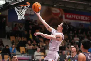 Ein Mann springt mit einem Basketball in Richtung Korb.