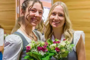 Zwei junge Damen in Dirndlkleidern mit Blumensträußen