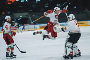 Ein Eishockeyspieler springt auf dem Eis in Richtung eines anderen Eishockeyspielers.