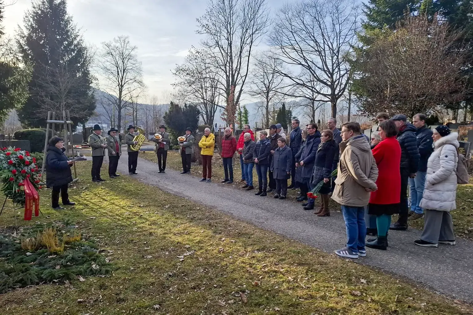Eine Gruppe von Personen und eine Musikkapelle auf einem Friedhof