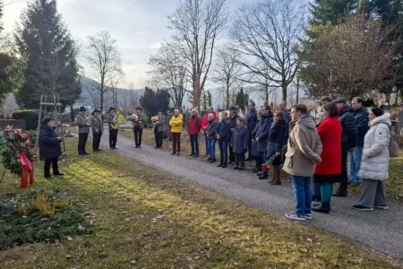 Eine Gruppe von Personen und eine Musikkapelle auf einem Friedhof