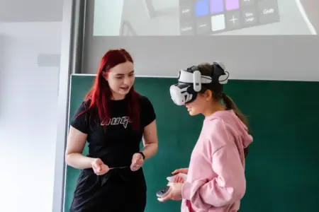 Zwei Mädchen vor einer Tafel, eine trägt eine Datenbrille