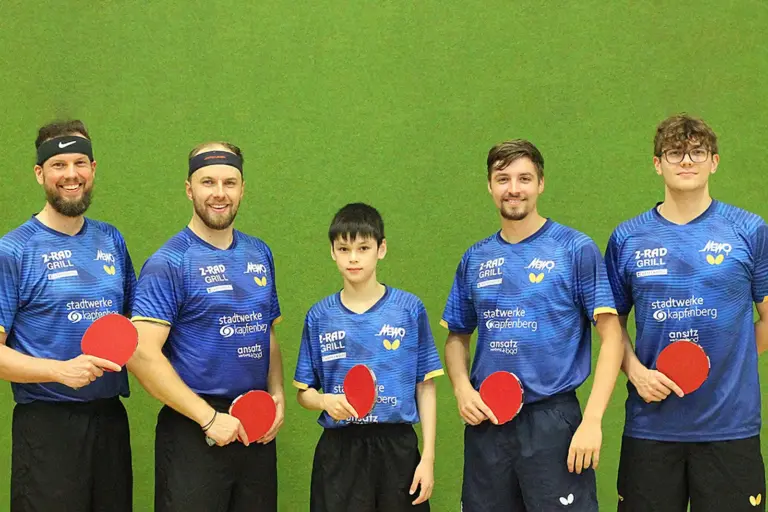 Fünf Männer mit je einem Tischtennisschläger in der Hand vor einer grünen Wand.