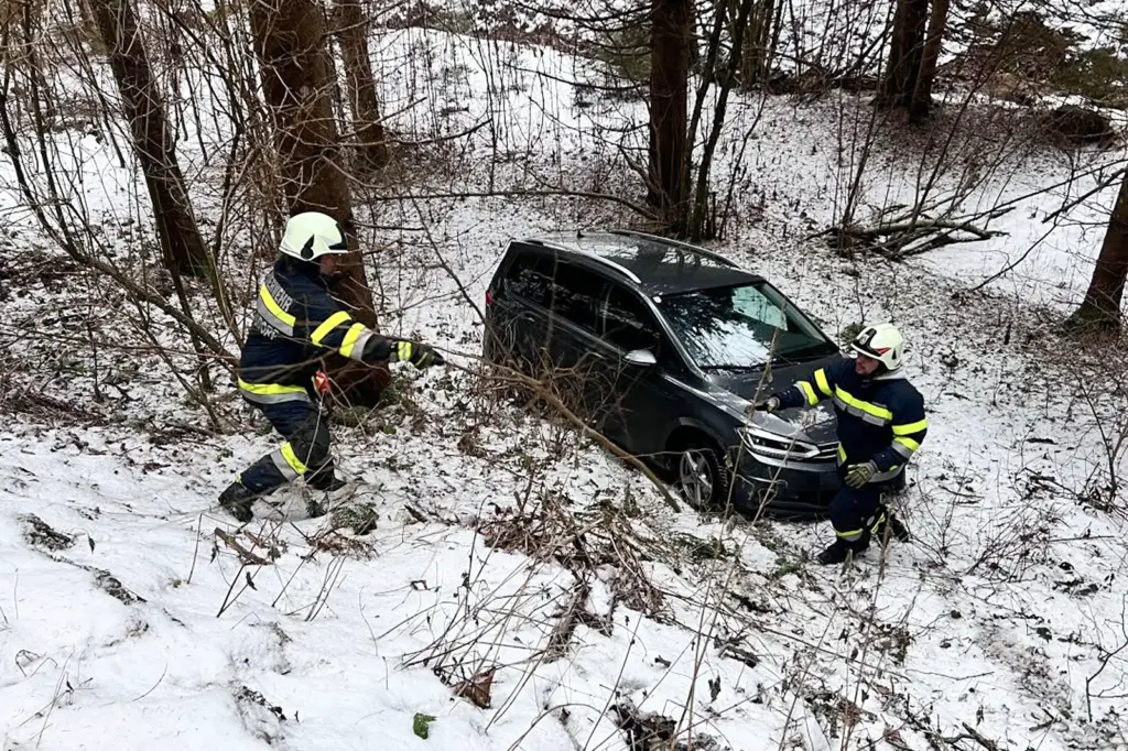 Ein Auto steht mit im Wald, daneben sind zwei Feuerwehrleute zu sehen.