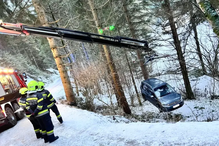 Ein Auto hängt am Kran eines Feuerwehrautos.