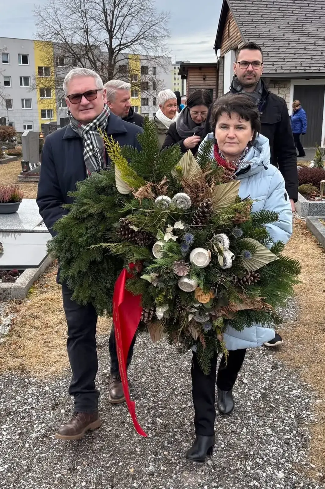 Ein Mann und eine Frau tragen einen Gedenkkranz