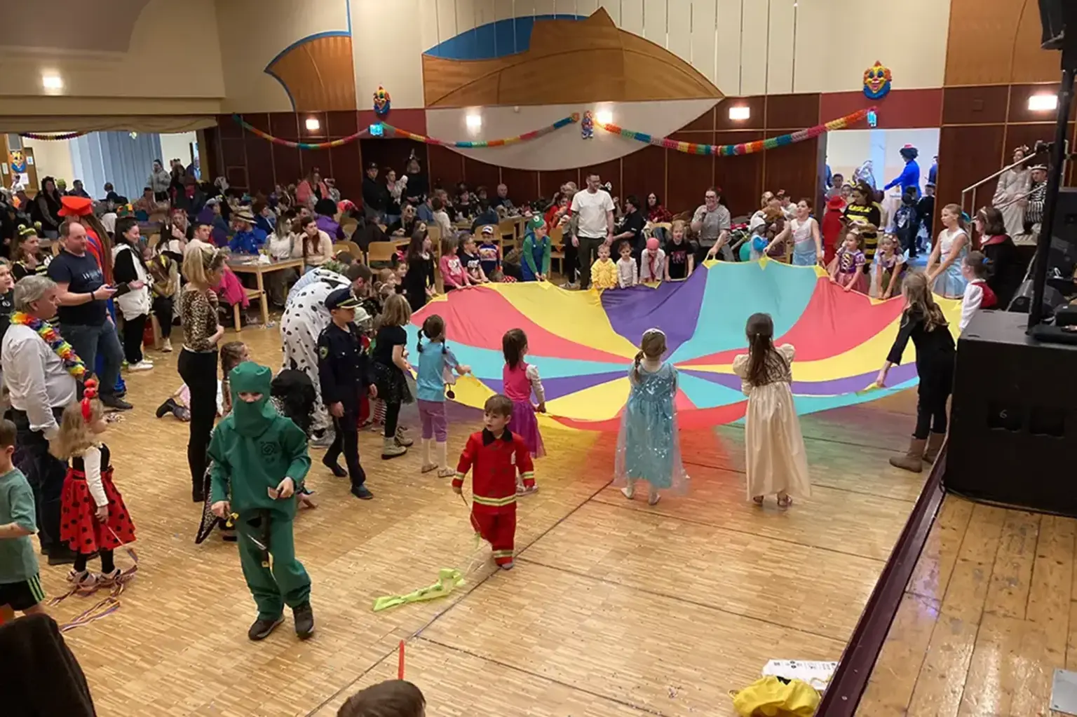Viele Kinder in Kostümen spielen in einem großen Saal