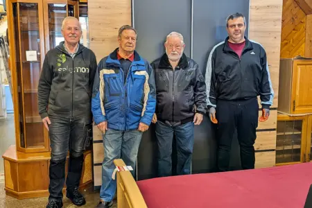 Vier ältere Männer vor einer Holzwand