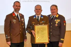 Drei Männer in Uniform halten eine Urkunde