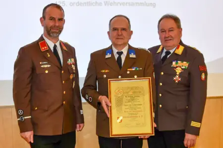 Drei Männer in Uniform halten eine Urkunde