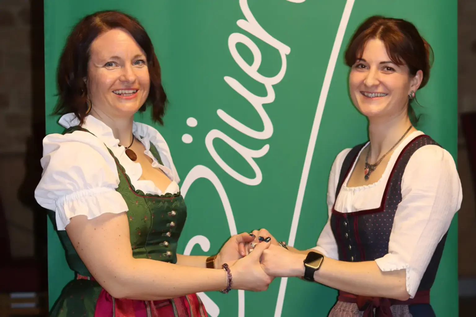 Zwei Frauen in Tracht halten sich an den Händen