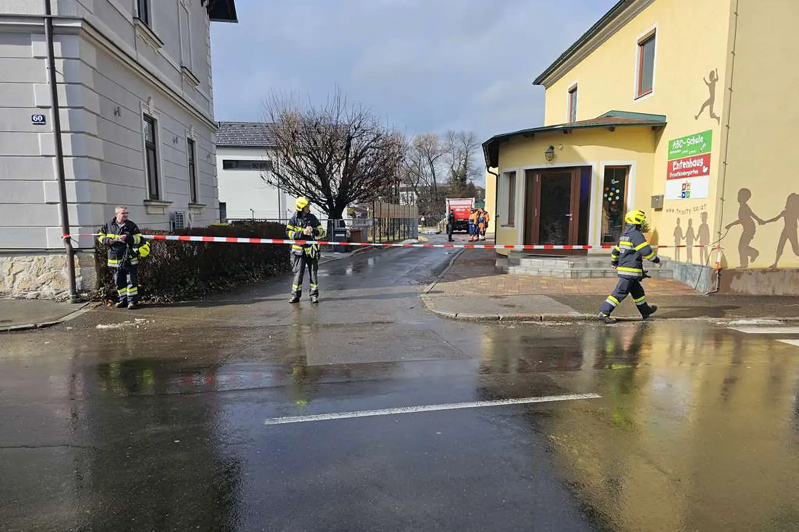 Mehere Männer in Uniformen bringen ein Absperrband über einer Straße an