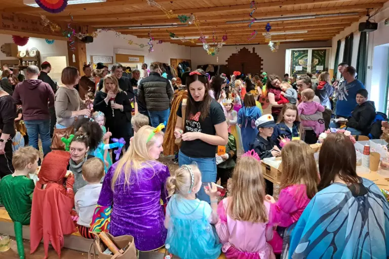 Ein großer Raum voller Menschen, viele davon in bunten Kostümen