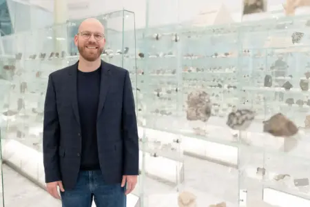 Ein Mann vor einer Vitrine voller Steine.