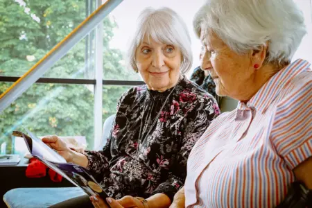 Zwei ältere Frauen blättern in einer Broschüre