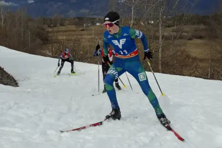 Ein Jugendlicher mit Langlaufski auf einer Loipe. Dahinter sind zwei weitere Jugendliche mit Langlaufski zu erkennen.