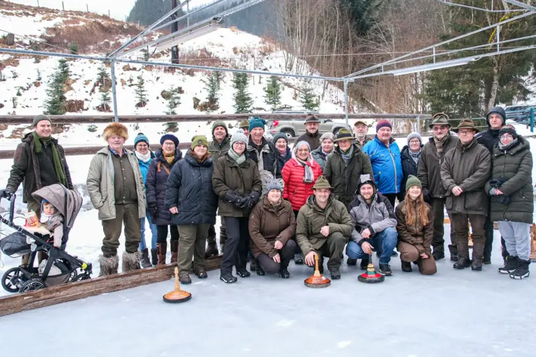 Eine Gruppe von Personen mit Eisstöcken auf einer Eisbahn