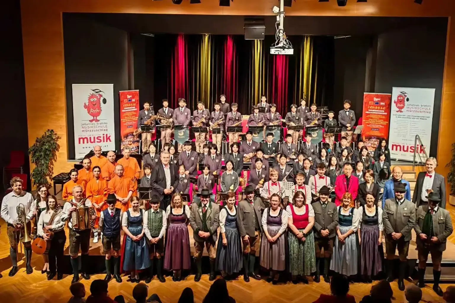 Zahlreiche Menschen mit Musikinstrumenten auf einer großen Bühne.