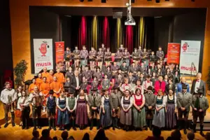 Zahlreiche Menschen mit Musikinstrumenten auf einer großen Bühne.