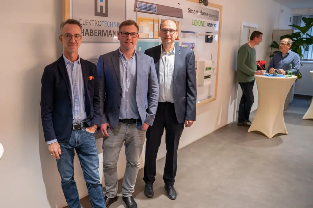 Drei Männer vor einem Firmenschild