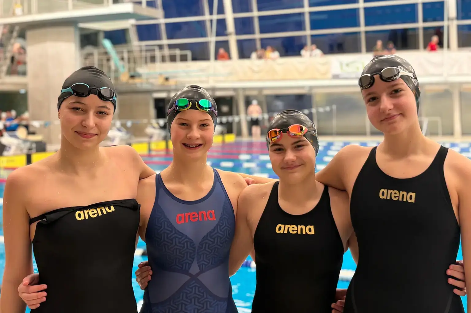Steirische Schwimm-Meister Vier junge Frauen in Schwimmanzügen in einem Hallen-Schwimmbad.