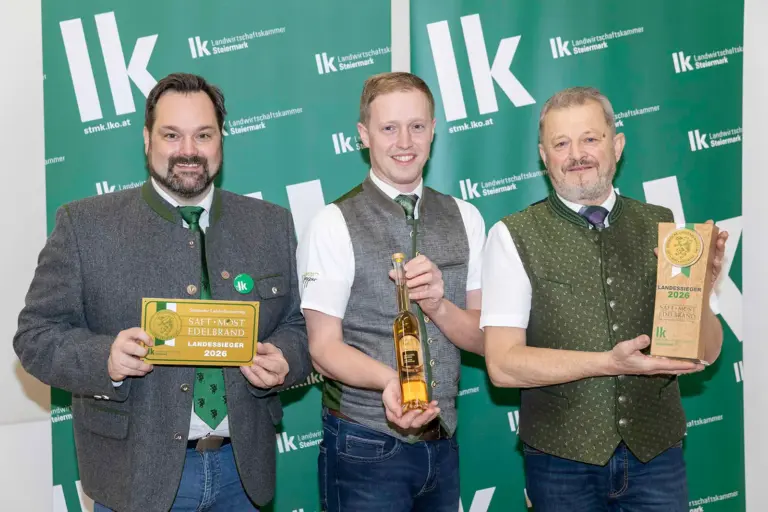 Drei Männer präsentieren eine Flasche und Preise