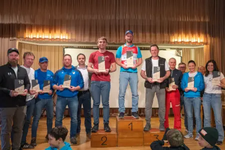 Gesamtsieger im Schibezirkscup V stehen fest Mehrere Männer und Frauen stehen nebeneinander auf einer Bühne, in der Mitte steht ein Siegerpodest, auf dem jeweils Menschen mit Pokalen stehen.