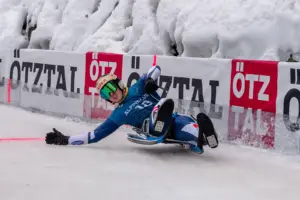 Ein Mann auf einer Rodel auf einer vereisten Strecke.