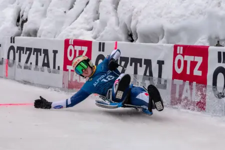 Ein Mann auf einer Rodel auf einer vereisten Strecke.