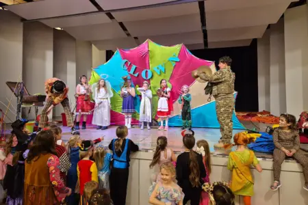 Viele Kinder in Kostümen und ein Clown auf einer Bühne