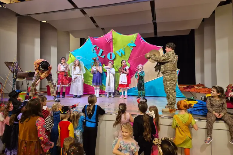 Kinderfasching mit Clown Jako Viele Kinder in Kostümen und ein Clown auf einer Bühne