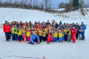 Eine große Gruppe von Kindern mit Erwachsenen in Schibekleidung im Schnee