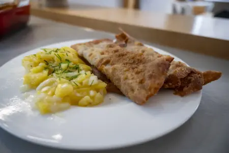Ein Teller mit Kartoffelsalat und zwei Veitscher Fleischkrapfen.